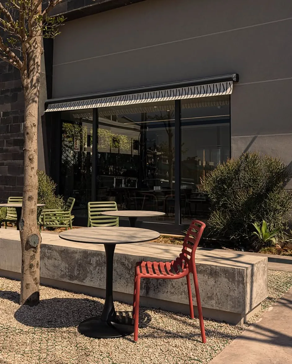 A Muscador storefront with outdoor seating under a patterned awning